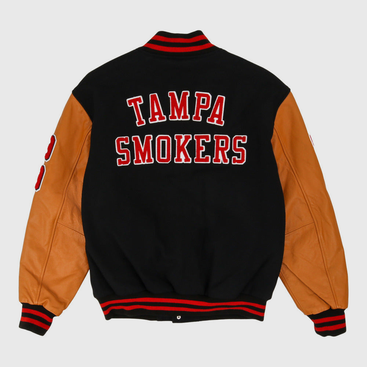 The Ebbets Field Tampa Smokers MiLB Dna Varsity Jacket features a black body, tan leather sleeves, red and white striped cuffs and collar, and 