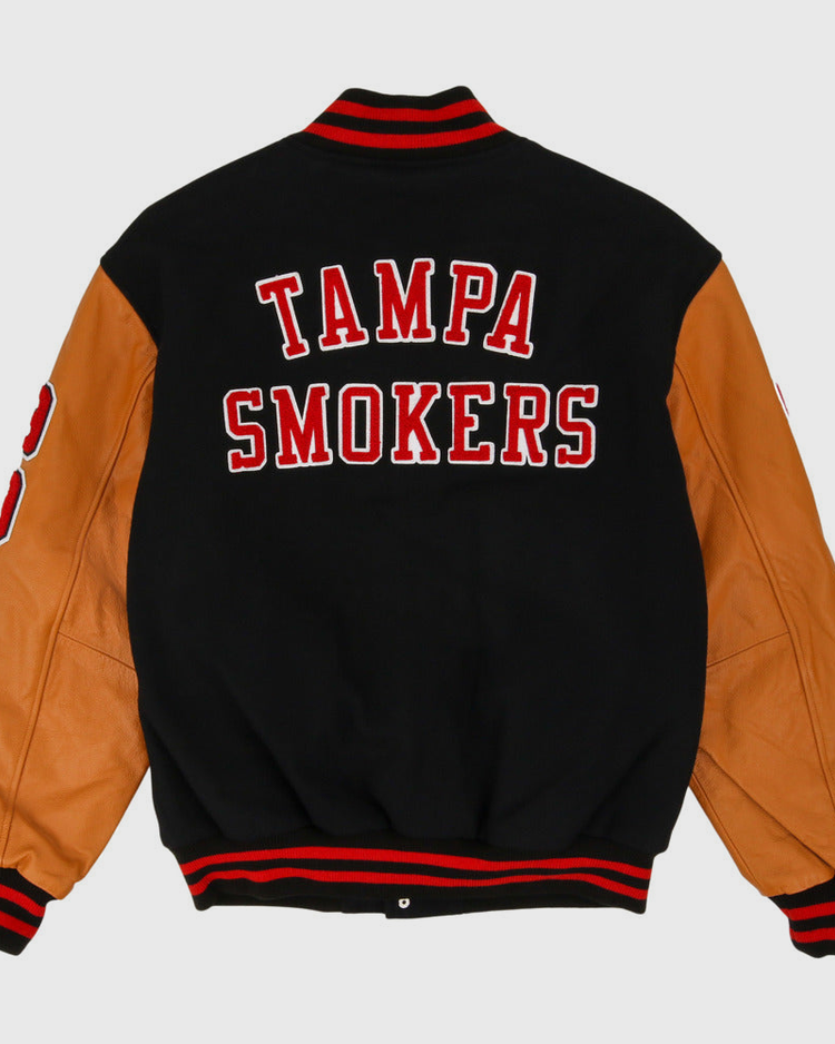The Ebbets Field Tampa Smokers MiLB Dna Varsity Jacket features a black body, tan leather sleeves, red and white striped cuffs and collar, and 