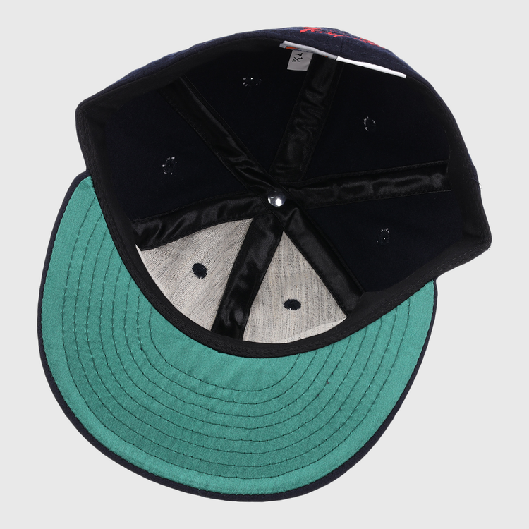 An inside view of the EFF Tampa Tarpons Letterhead Wool Vintage Ballcap, featuring a green underbrim, black interior seams, gray sweatband, and visible size tag—shown upside down with the crown facing up.