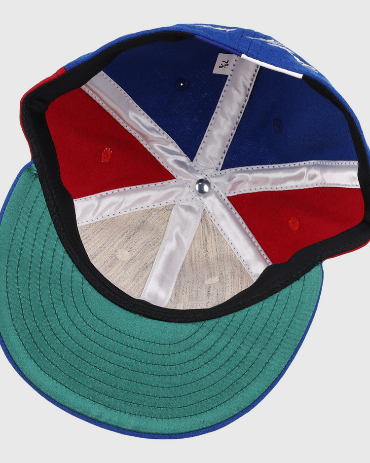 The inside of the Ebbets Field Flannels Tim Raines Signature Series Ballcap features green underbill, red and blue panels, white stitching, a silver crown button, and a visible size tag.