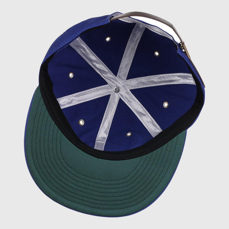 An overhead view of the EFF Trois Rivières Royals Cotton Twill Ballcap shows its royal blue cotton interior, green underbrim, grey adjustable strap, white stitched crown bands, and metal ventilation holes.