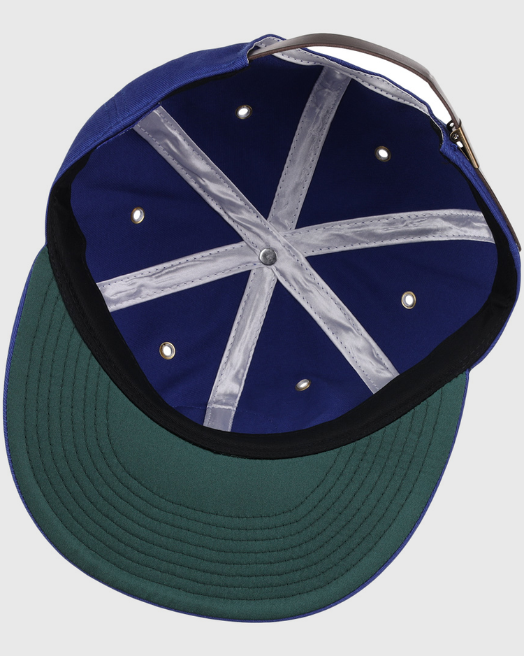 An overhead view of the EFF Trois Rivières Royals Cotton Twill Ballcap shows its royal blue cotton interior, green underbrim, grey adjustable strap, white stitched crown bands, and metal ventilation holes.