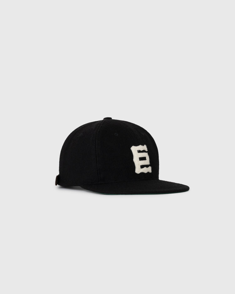 The EFF Tokyo Kyojin (Giants) 1940 Authentic Wool Softbrim Ballcap is a black wool cap with a flat brim and a white, stylized E on the front, shown against a plain light gray background.