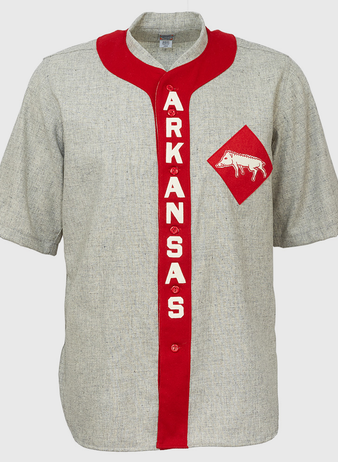 The EFF University of Arkansas 1912 Road Jersey is a gray, short-sleeve college baseball shirt with a red vertical stripe reading ARKANSAS in white and a red diamond patch featuring a white razorback logo—an authentic vintage reproduction.