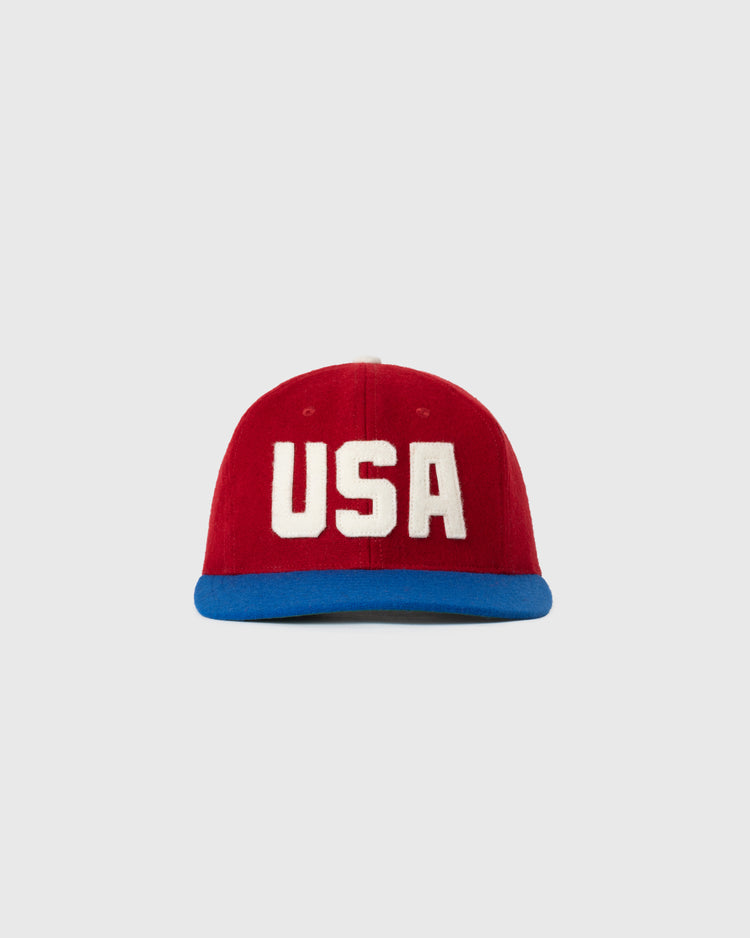 The EFF USA National Team 1956 Authentic Wool Ballcap features a red crown, bold white USA on the front, and a blue brim, shown on a plain light gray background—ideal for fans seeking a classic replica look.