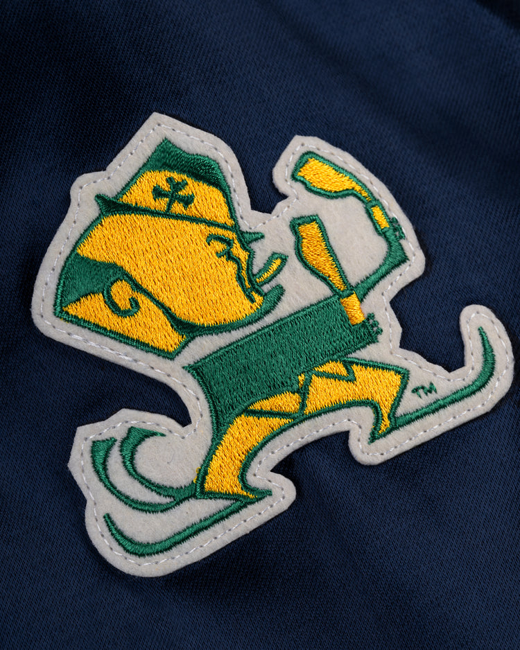 A vintage-inspired embroidered leprechaun mascot patch decorates the dark blue University of Notre Dame Satin Windbreaker Jacket by EFF—perfect for fans seeking unique team style.