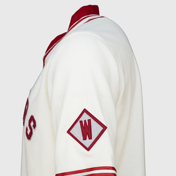 A close-up side view of the EFF Washington State University 1937 Home Jersey, showcasing white fabric with red accents, a red diamond patch with a white W on the sleeve, and classic red lettering authentic to WSU.