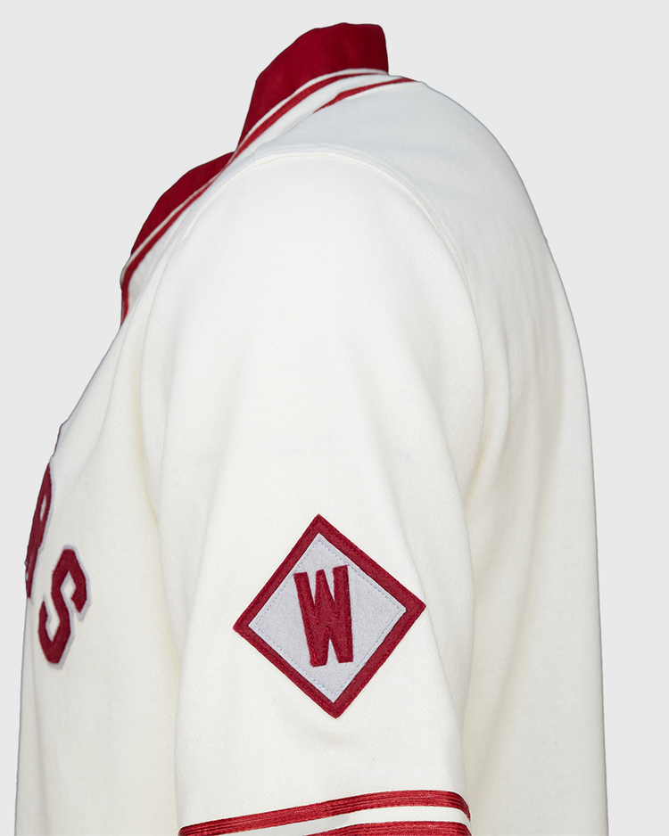 A close-up side view of the EFF Washington State University 1937 Home Jersey, showcasing white fabric with red accents, a red diamond patch with a white W on the sleeve, and classic red lettering authentic to WSU.