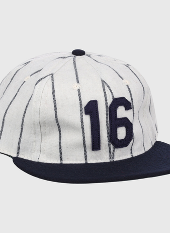 The Ebbets Field Flannels Whitey Ford Signature Series Ballcap is a vintage-style white wool cap with navy vertical pinstripes, a navy brim, and the number 16 in bold navy on the front.