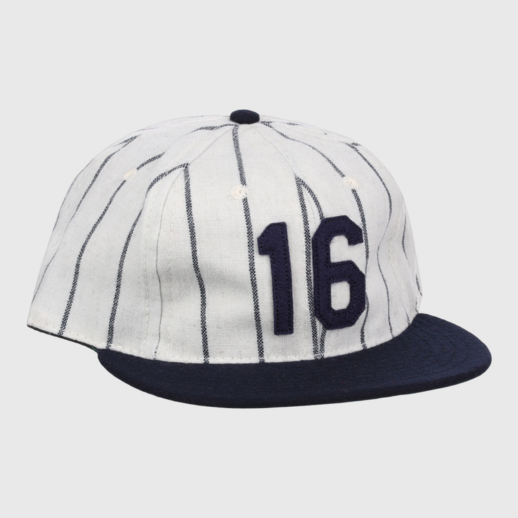 The Ebbets Field Flannels Whitey Ford Signature Series Ballcap is a vintage-style white wool cap with navy vertical pinstripes, a navy brim, and the number 16 in bold navy on the front.