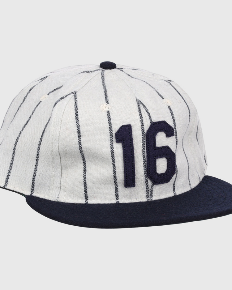 The Ebbets Field Flannels Whitey Ford Signature Series Ballcap is a vintage-style white wool cap with navy vertical pinstripes, a navy brim, and the number 16 in bold navy on the front.