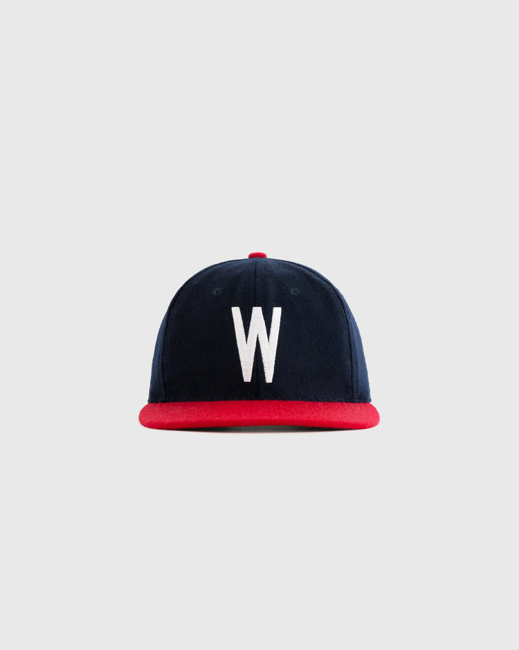 The Wichita Braves 1957 Authentic Wool Ballcap by Ebbets Field Flannels features navy wool, a red brim, and a bold white W on the front, shown against a plain light gray background.