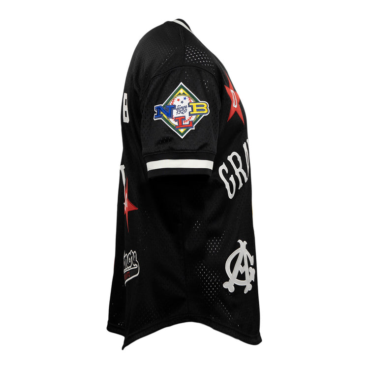 The EFF Negro League Allover Vintage Inspired NL Replica V-Neck Mesh Jersey in black features white accents, red stars, colorful patches—including a diamond-shaped sleeve patch—and stylized white lettering, reflecting classic Negro League Baseball mesh jersey style.