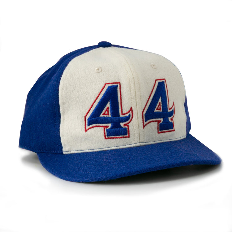 The Hank Aaron 1973 Signature Series Ballcap by Ebbets Field Flannels is a vintage-style wool cap, made in the USA, featuring blue/white panels and “44” in blue and red outlined on the front.