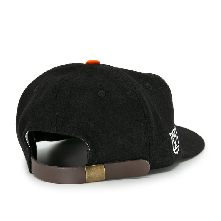 The EFF Baltimore Clippers 1962 Vintage Ballcap features black wool, a brown adjustable strap with brass buckle, and a small white embroidered logo—a timeless nod to the AHL team’s heritage.