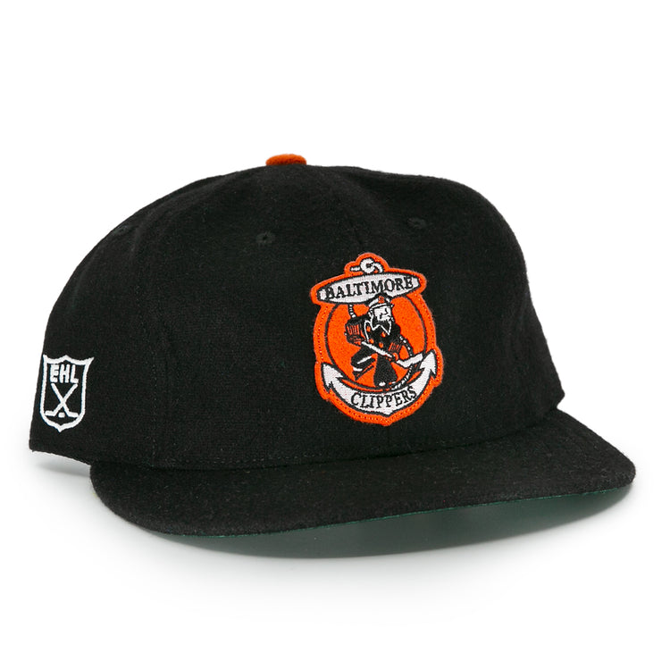 The EFF Baltimore Clippers 1962 Vintage Ballcap is a black wool cap with the team’s sailor-and-hockey-stick logo on front, an EHL shield embroidered on the side, and an orange top button.