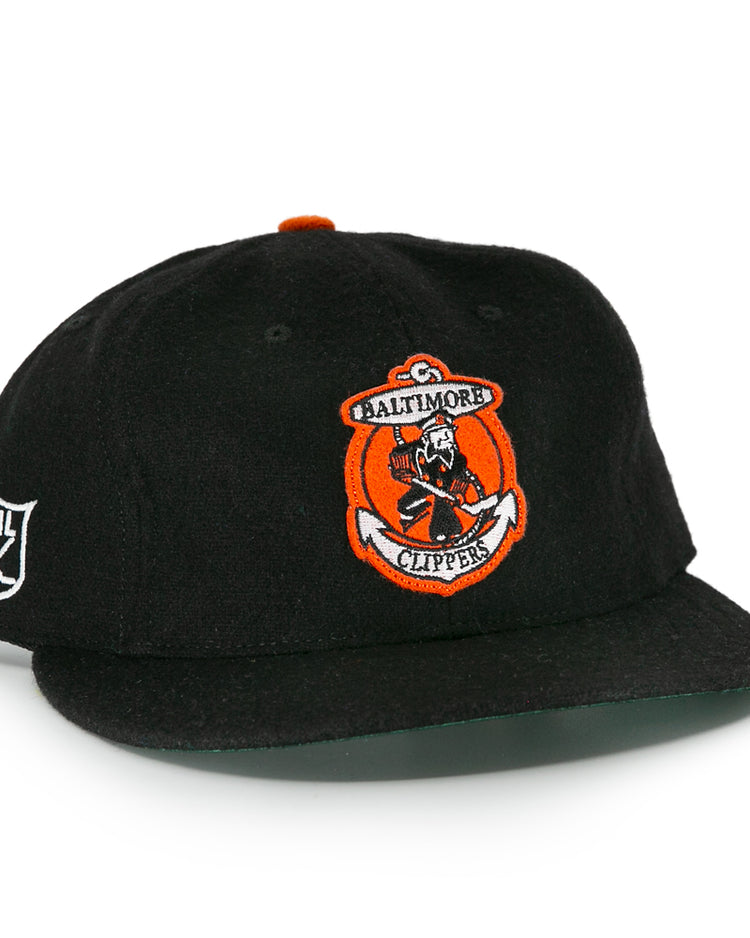 The EFF Baltimore Clippers 1962 Vintage Ballcap is a black wool cap with the team’s sailor-and-hockey-stick logo on front, an EHL shield embroidered on the side, and an orange top button.