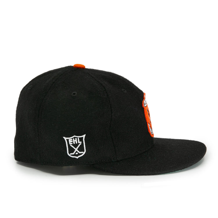 The EFF Baltimore Clippers 1962 Vintage Ballcap is a black wool cap with an orange front logo and a white shield-shaped EHL emblem on the side, inspired by the original team, shown from a side angle against a white background.