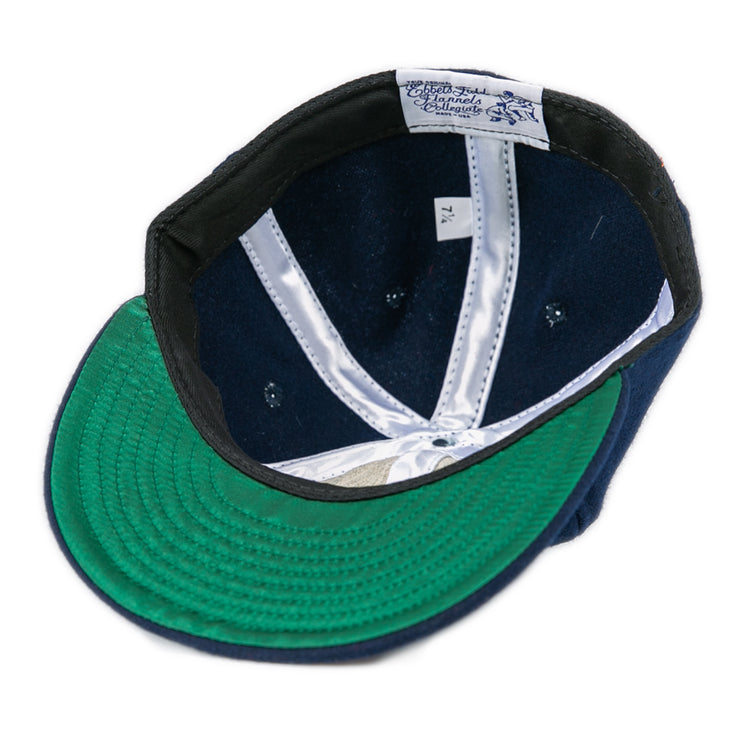 A Bucknell University 1965 Vintage Ballcap by EFF, navy wool and made in the USA, turned inside out to show its green brim underside, white satin lining, and a size 7 1/4 tag.