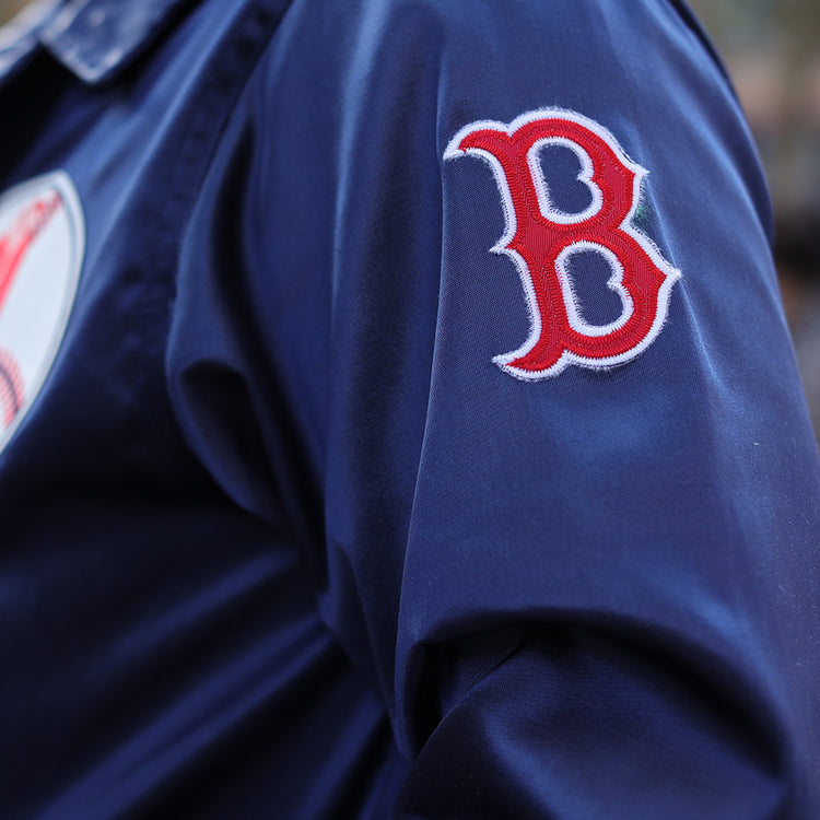 Close-up of a person in the EFF Boston Red Sox 1967 Satin Windbreaker, featuring a navy blue design and red and white B logo patch on the sleeve for iconic MLB vintage style.