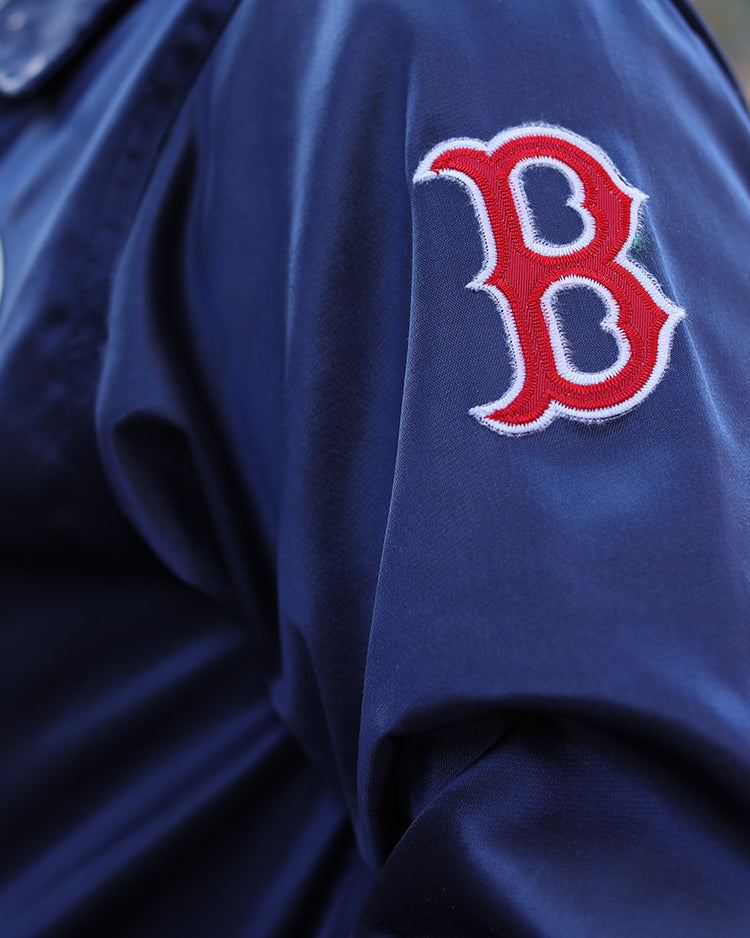Close-up of a person in the EFF Boston Red Sox 1967 Satin Windbreaker, featuring a navy blue design and red and white B logo patch on the sleeve for iconic MLB vintage style.