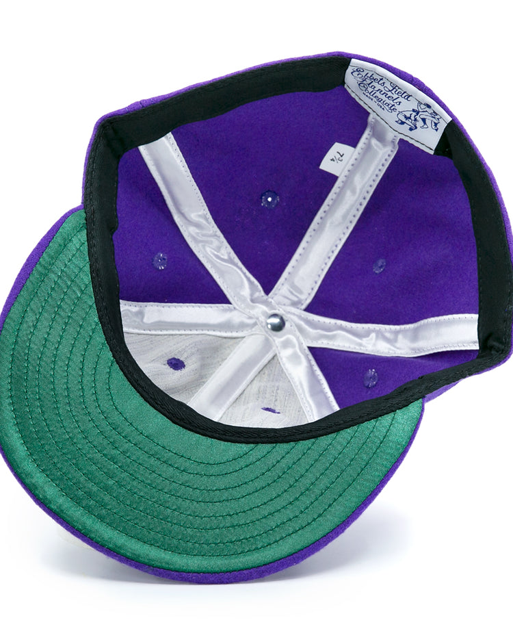 The EFF Cleveland Falcons 1936 Vintage Ballcap is a purple wool cap shown upside down, displaying its green underbrim, white inner lining, sewn crown labels, and an adjustable leather strap.