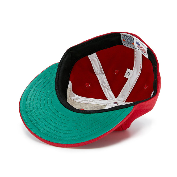 A Daiei Stars 1949 Vintage Ballcap by EFF in red is shown upside down, revealing the green underside of the brim, black inner band, white crown seams, size label, and American flag tag—a classic for Nippon Professional Baseball fans.