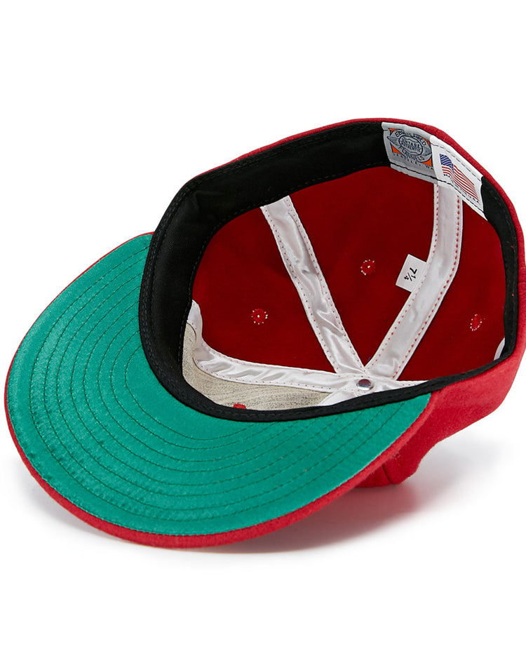 A Daiei Stars 1949 Vintage Ballcap by EFF in red is shown upside down, revealing the green underside of the brim, black inner band, white crown seams, size label, and American flag tag—a classic for Nippon Professional Baseball fans.