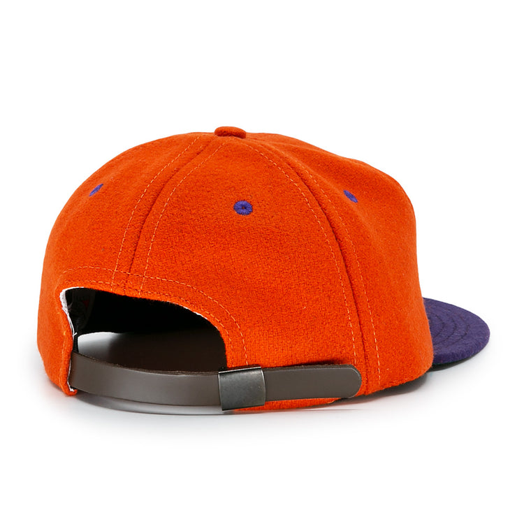 The Hershey Sport Club 1956 Vintage Ballcap by Ebbets Field Flannels is an orange wool cap with a purple brim, purple stitching on orange fabric, and a brown adjustable strap. Shown from the back.