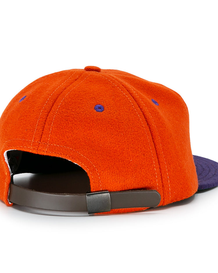 The Hershey Sport Club 1956 Vintage Ballcap by Ebbets Field Flannels is an orange wool cap with a purple brim, purple stitching on orange fabric, and a brown adjustable strap. Shown from the back.