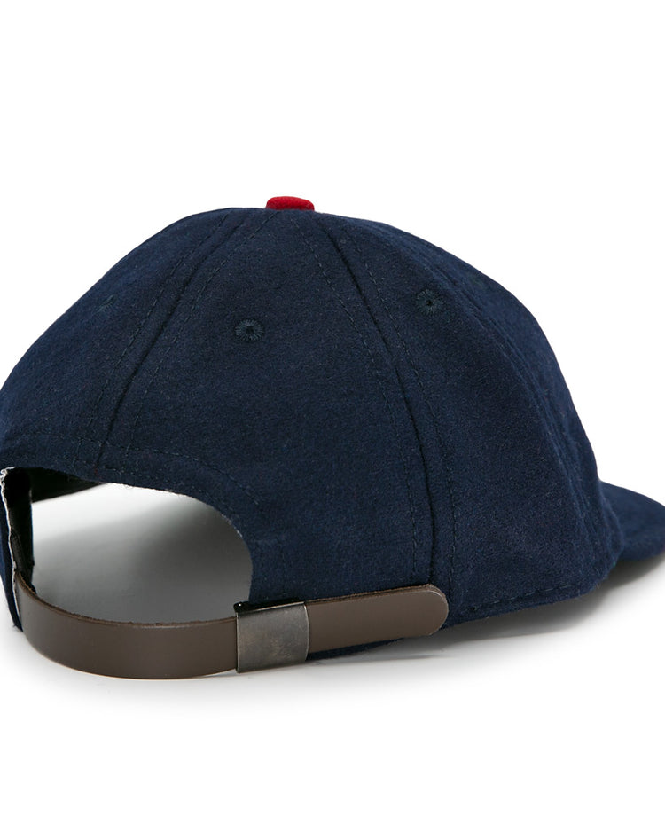 The EFF Houston Buffs 1932 Vintage 8-Panel Ballcap is a navy blue wool cap with a brown adjustable strap and metal clasp, red top button, and classic design details inspired by vintage baseball caps.