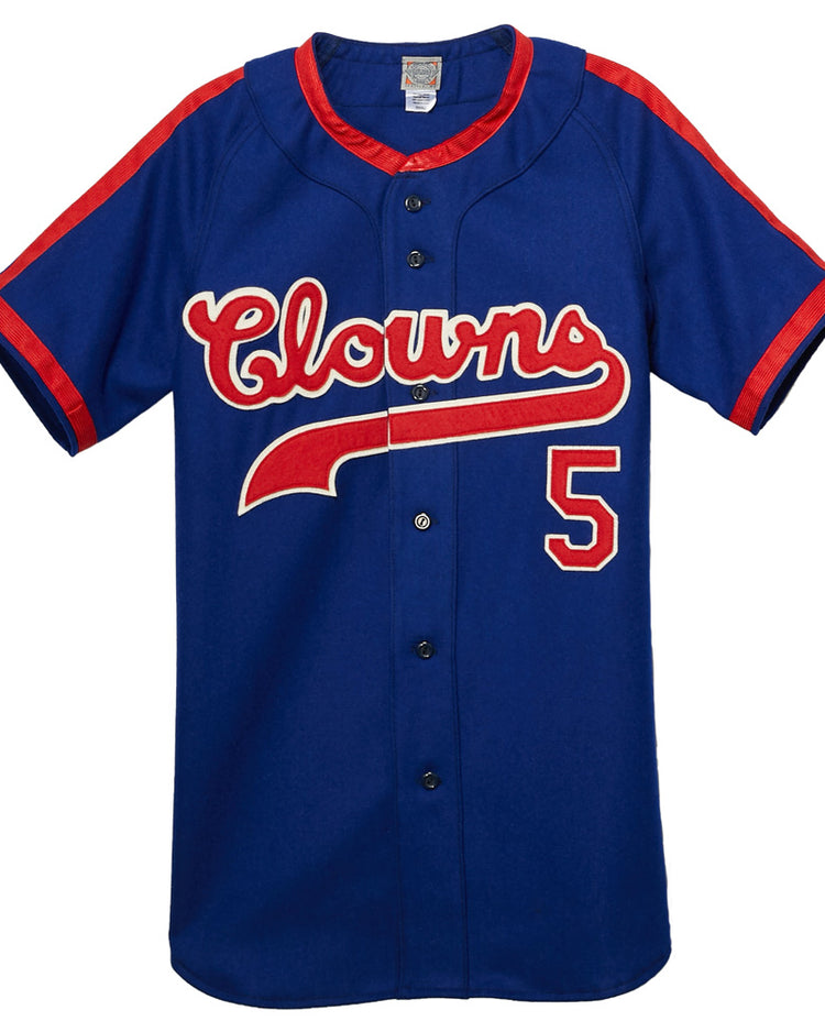 The EFF Indianapolis Clowns 1952 Road Jersey is a blue button-up with red trim, “Clowns” in white and red script across the chest, and number 5 on the lower right—honoring Henry Aaron’s time in the Negro Leagues.