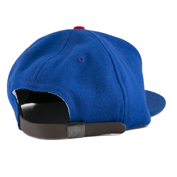 The EFF Jersey City Giants 1946 Vintage Ballcap is a blue wool cap with a red top button, visible stitching, and a brown adjustable strap with metal clasp, shown here from the back for classic vintage style.
