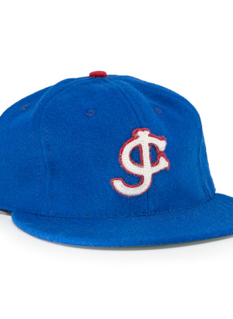 The EFF Jersey City Giants 1946 Vintage Ballcap is blue wool, featuring a white and red outlined interlocking J and C logo on the front and a red top button—faithful to the classic design.