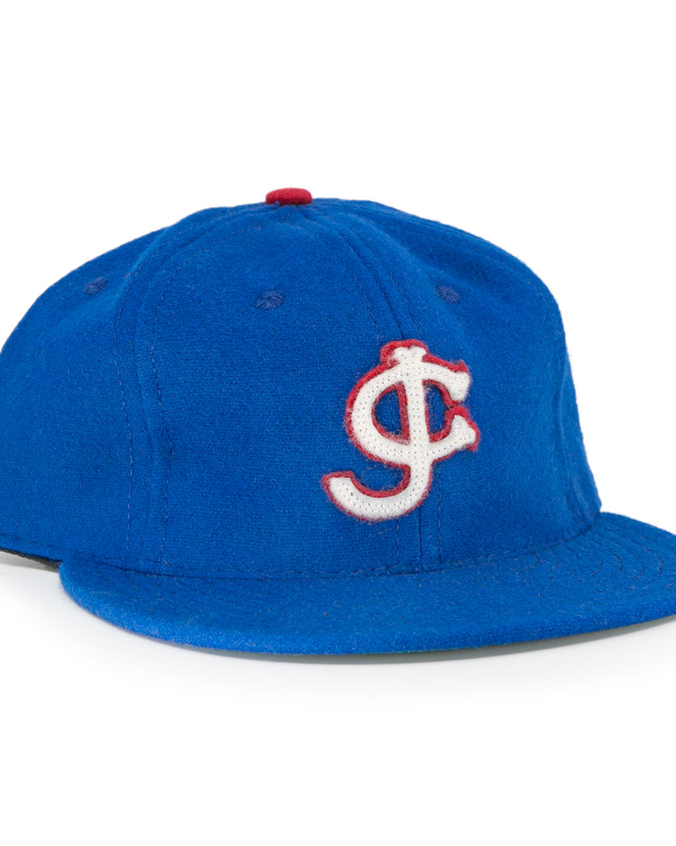 The EFF Jersey City Giants 1946 Vintage Ballcap is blue wool, featuring a white and red outlined interlocking J and C logo on the front and a red top button—faithful to the classic design.
