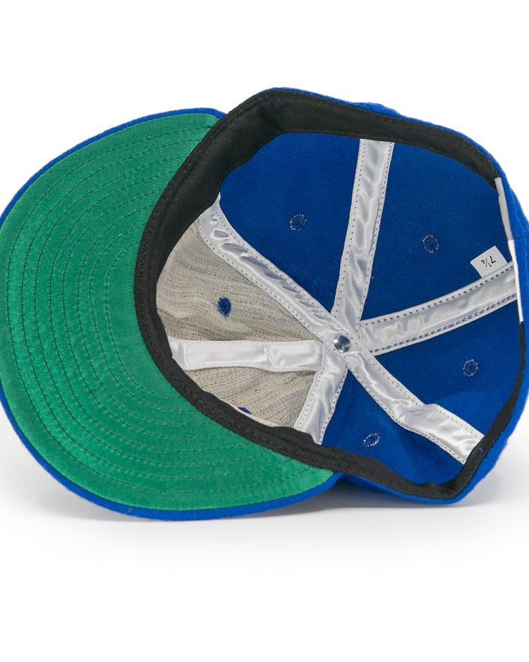 A look inside the EFF Jersey City Giants 1946 Vintage Ballcap reveals a blue cap with green brim, black inner band, white mesh lining, X-pattern white fabric strips, and a visible size tag.