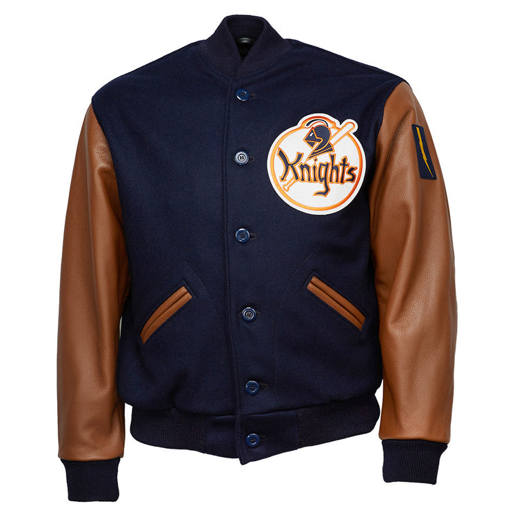 The EFF New York Knights 1939 Authentic Jacket features navy melton wool, brown leather sleeves, front pockets, a large Knights patch on the left chest, button-up front, and ribbed cuffs and waistband for a classic varsity look.