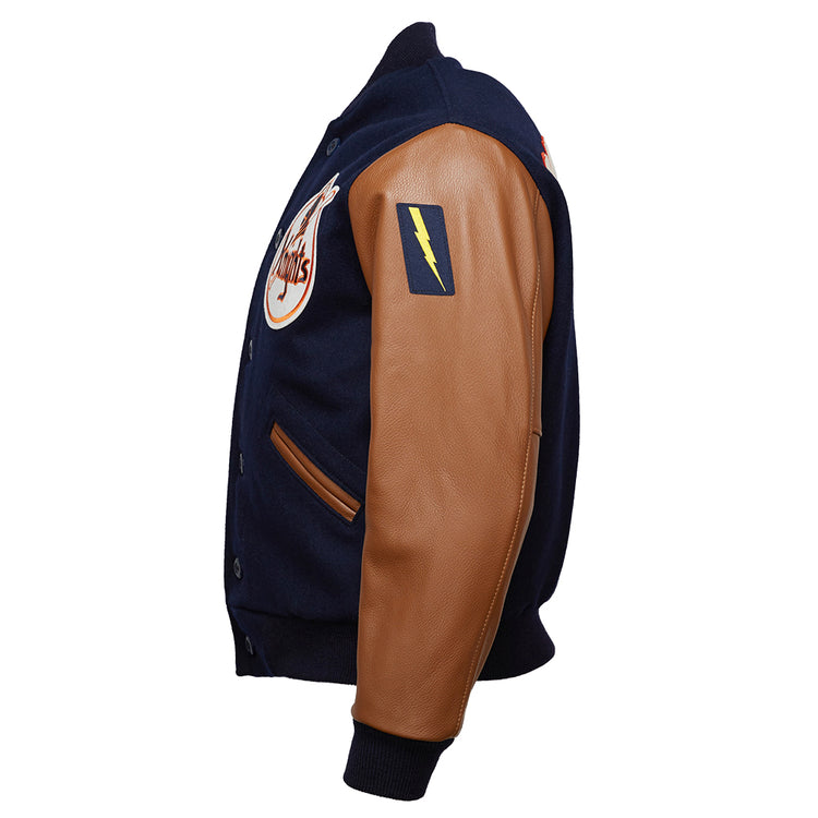 The EFF New York Knights 1939 Authentic Jacket is a navy melton wool varsity jacket with tan leather sleeves, a yellow lightning bolt patch on the upper arm, and a circular chest logo, shown from a side angle.