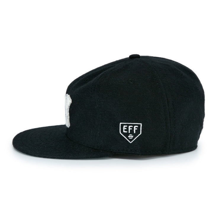 The New York Black Yankees Vintage Inspired Ballcap by EFF is a black cap with a flat brim, shown side-on, featuring a small white patch with EFF and a symbol embroidered on the side.