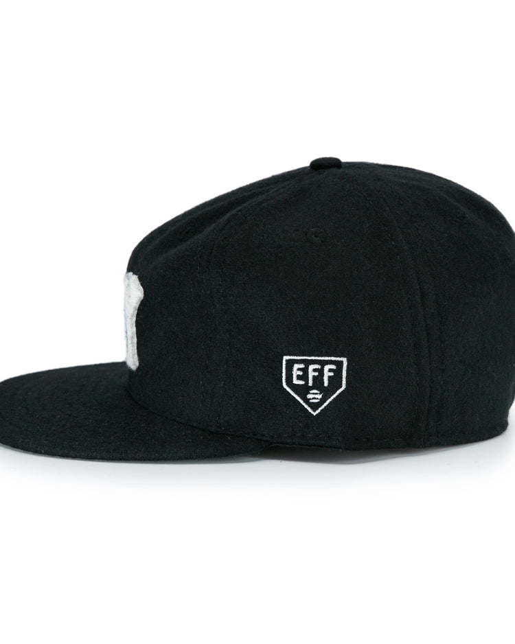 The New York Black Yankees Vintage Inspired Ballcap by EFF is a black cap with a flat brim, shown side-on, featuring a small white patch with EFF and a symbol embroidered on the side.