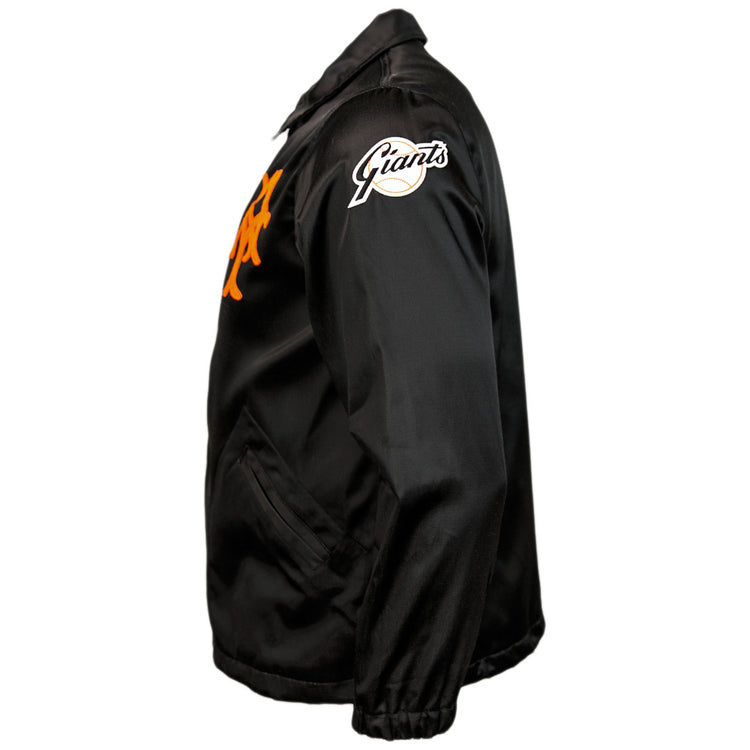 The EFF New York Giants 1954 Satin Windbreaker features a black satin finish, orange chest logo, white Giants sleeve patch, collar, pockets, and elastic cuffs—shown from the side in true vintage MLB style.