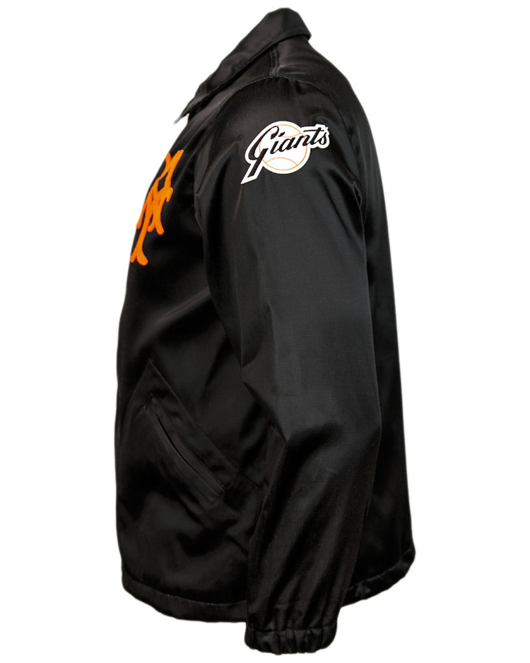 The EFF New York Giants 1954 Satin Windbreaker features a black satin finish, orange chest logo, white Giants sleeve patch, collar, pockets, and elastic cuffs—shown from the side in true vintage MLB style.