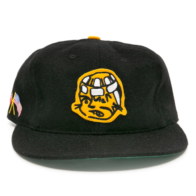 The EFF Pittsburgh Hornets 1953 Vintage Ballcap is a black wool hat featuring a yellow cartoon helmet logo on the front, plus an American flag and yellow ribbon patch on the side, inspired by classic hockey style.