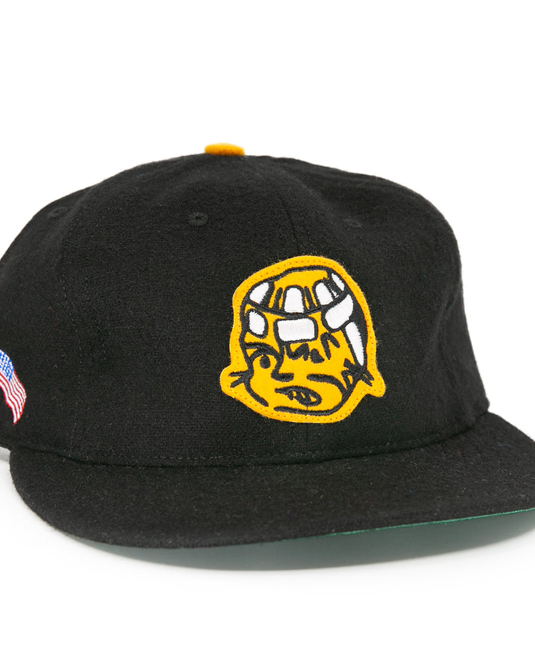 The EFF Pittsburgh Hornets 1953 Vintage Ballcap is a black wool hat featuring a yellow embroidered cartoon face on the front and American and Japanese flags on the side, inspired by classic Hornets style.
