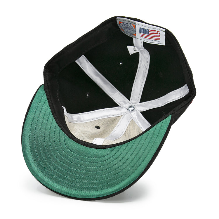 The underside of the Pittsburgh Hornets 1953 Vintage Ballcap by EFF features a green brim, white internal stitching, mesh sweatband, and two labels—one with an American flag and another with EFFs Pittsburgh Hornets branding.