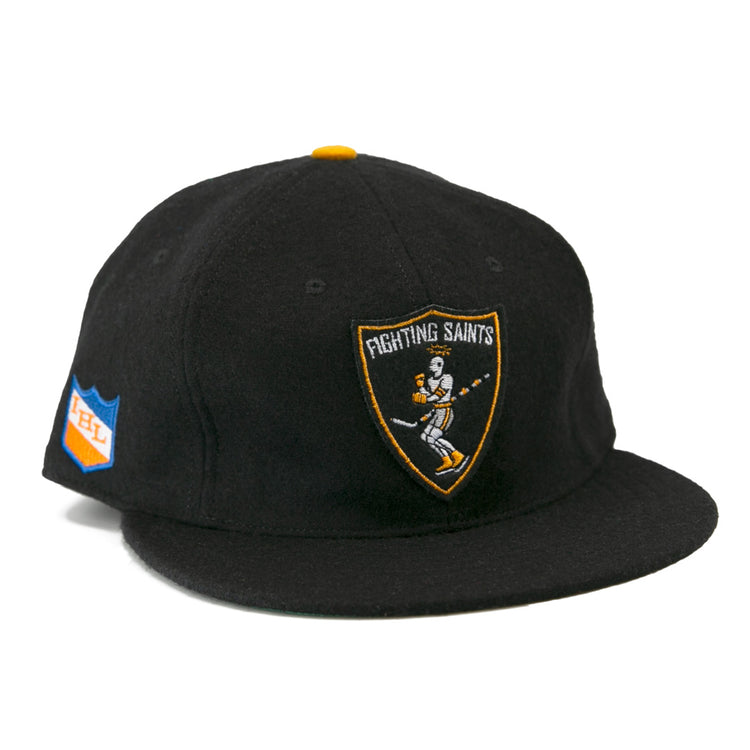 The EFF St. Paul Fighting Saints 1961 Vintage Ballcap is a black cap featuring a skeleton-hockey-stick Fighting Saints logo on the front and a blue/orange shield patch on the side—ideal for any Saints hockey fan.