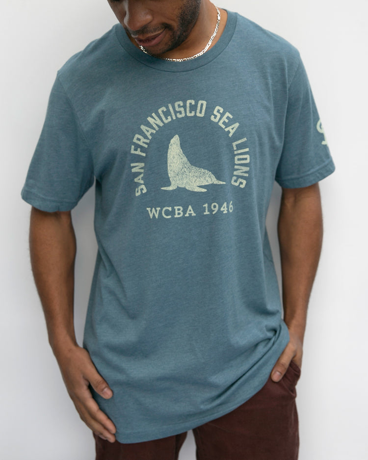 A man wears the EFF San Francisco Sea Lions 1946 T-Shirt, featuring a graphic sea lion and San Francisco Sea Lions WCBA 1946, celebrating the West Coast Baseball Association, against a plain white background.