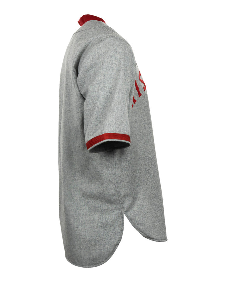 Side view of the EFF University of Wisconsin 1930 Road Jersey, a vintage gray baseball jersey with red collar and sleeve trim, textured fabric, curved hem, and partially visible red front lettering.