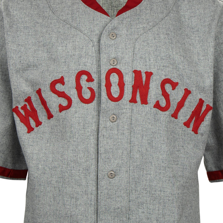 The EFF University of Wisconsin 1930 Road Jersey is a gray button-up with WISCONSIN in bold red letters and red trim, inspired by an authentic 1930 Badgers baseball jersey.