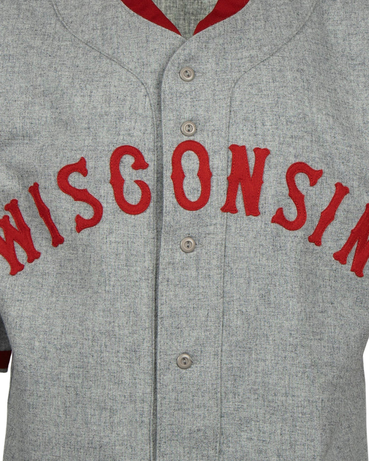 The EFF University of Wisconsin 1930 Road Jersey is a gray button-up with WISCONSIN in bold red letters and red trim, inspired by an authentic 1930 Badgers baseball jersey.